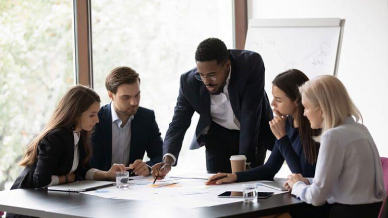 Confident african American male boss work cooperate with diverse team at office briefing, focused biracial businessman head meeting, collaborate discuss business ideas with colleagues at meeting