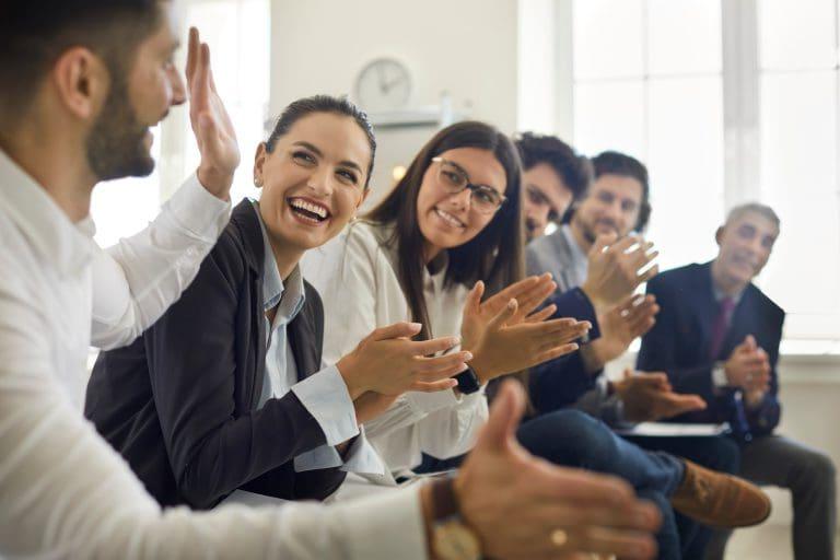一群人在专业的商务会议或研讨会上感谢演讲者有趣的演讲. 在公司会议上，一群快乐的男女员工在为同事鼓掌